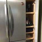 A narrow cabinet was built to fit between the refrigerator and the wall efficiently using all the space.